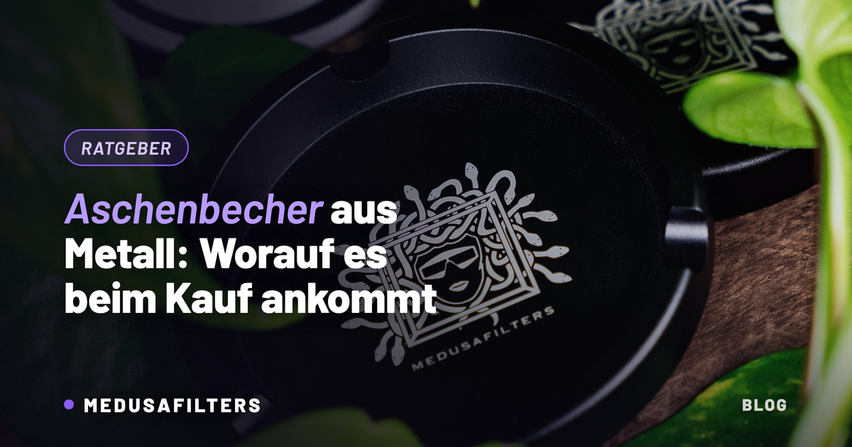 Aschenbecher aus Metall in Schwarz mit Medusafilters-Logo auf Holz zwischen Pflanzenblättern